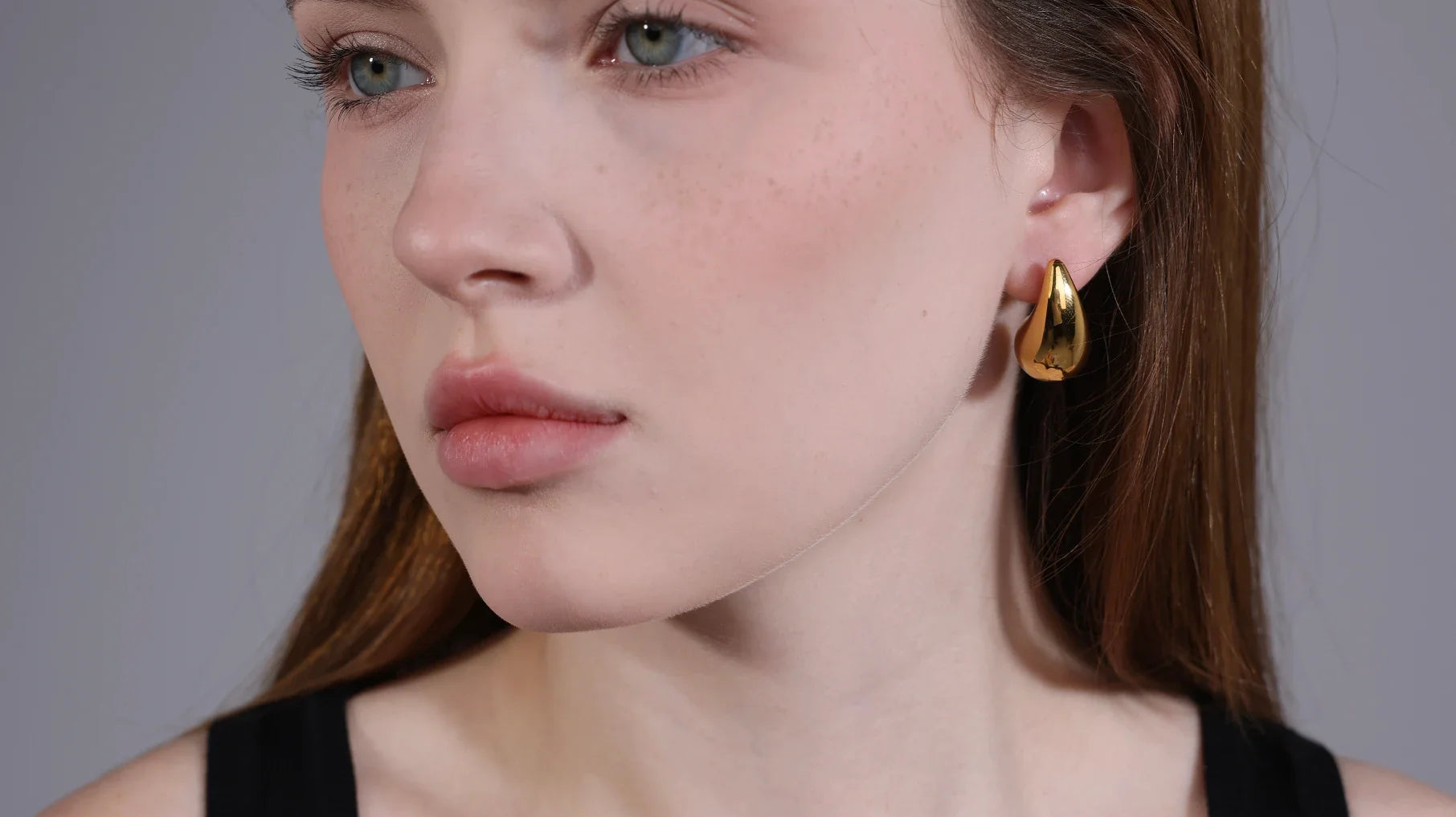 Model wearing chunky gold hoops – 18K gold plated jewelry by Velvet Luminance, hypoallergenic and tarnish resistant.