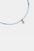 close-up of aquamarine seed beads with gold-framed teardrop pendant