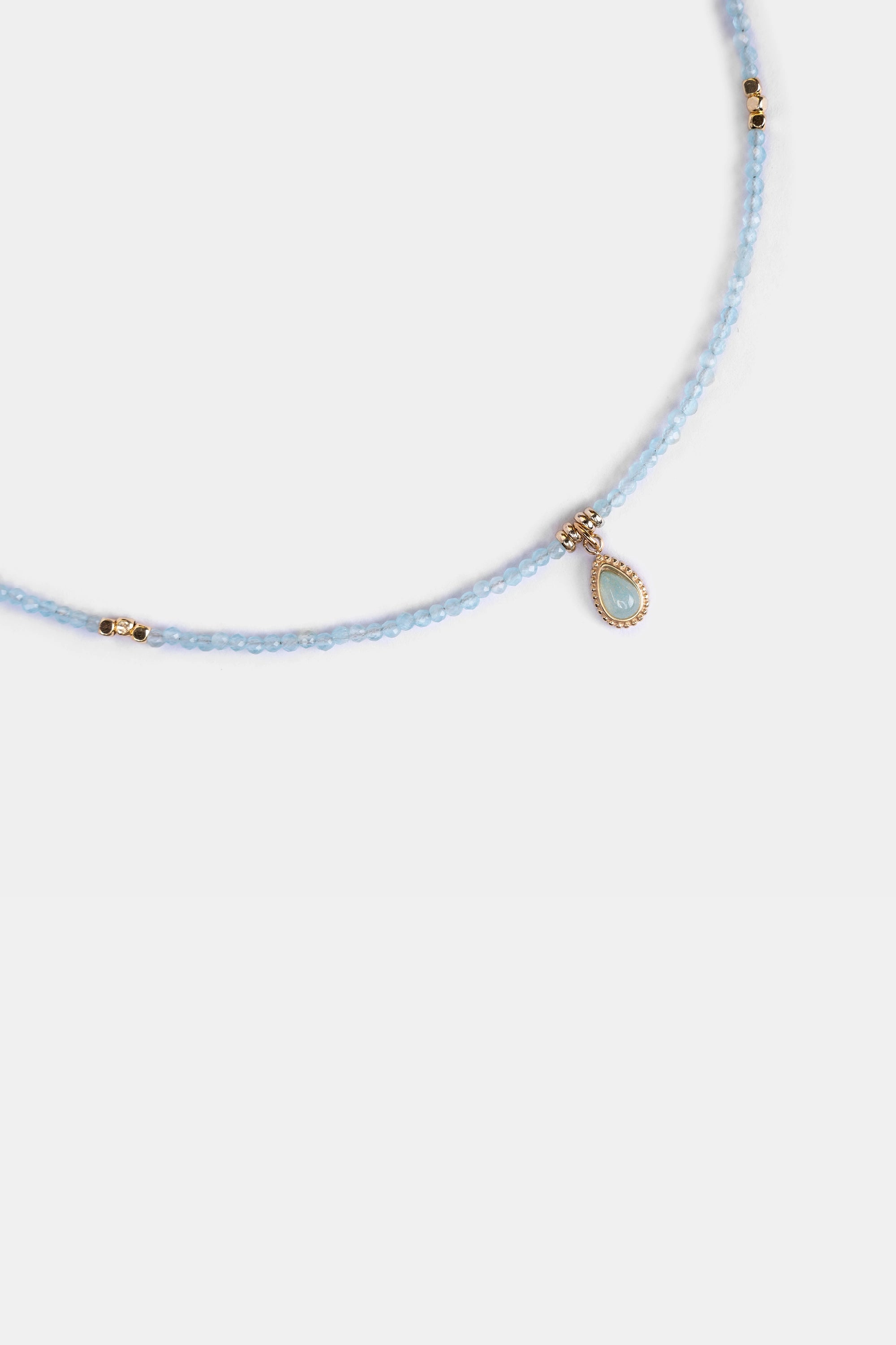 close-up of aquamarine seed beads with gold-framed teardrop pendant