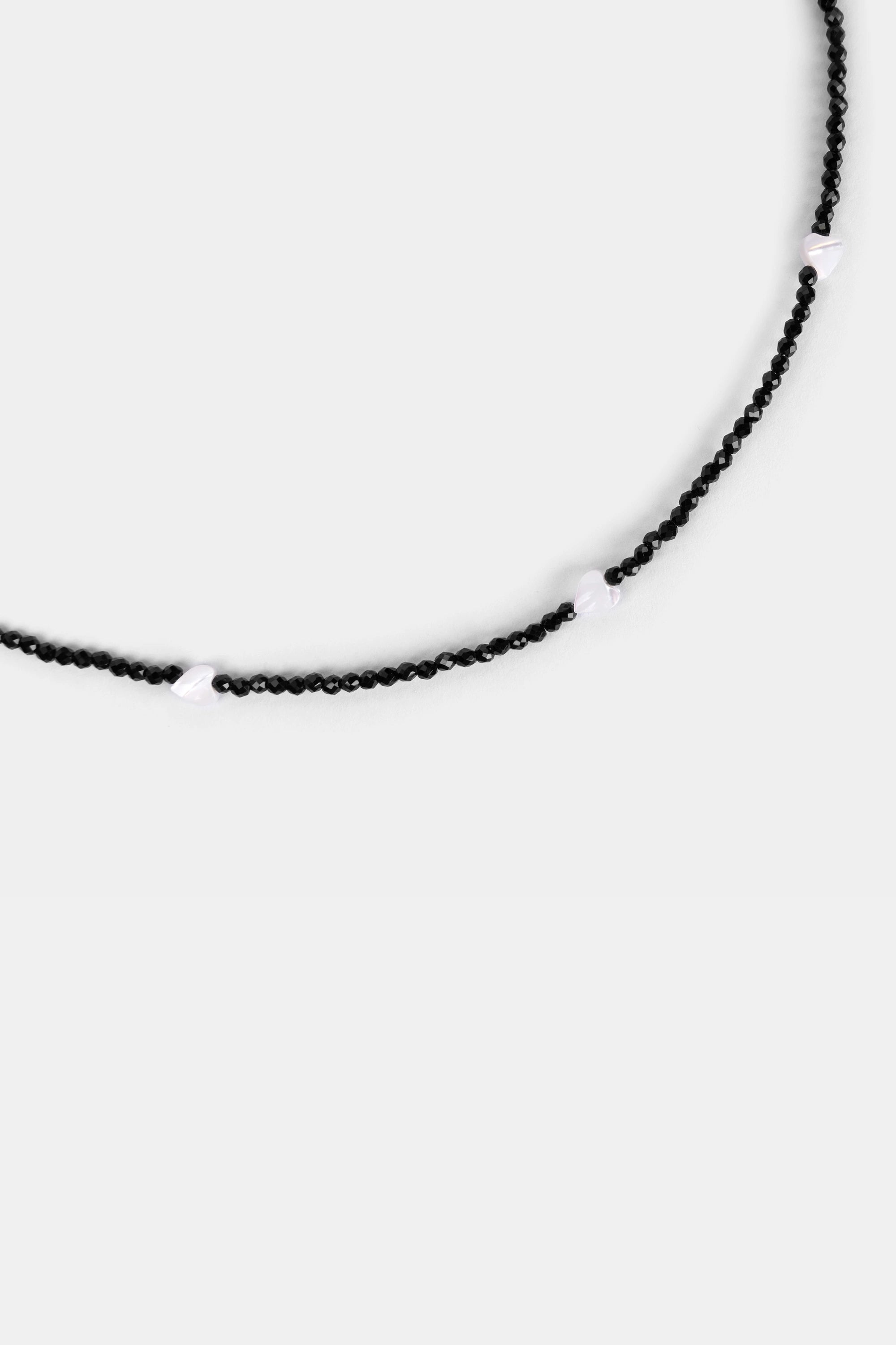 close-up of black faceted seed beads with white shell heart beads