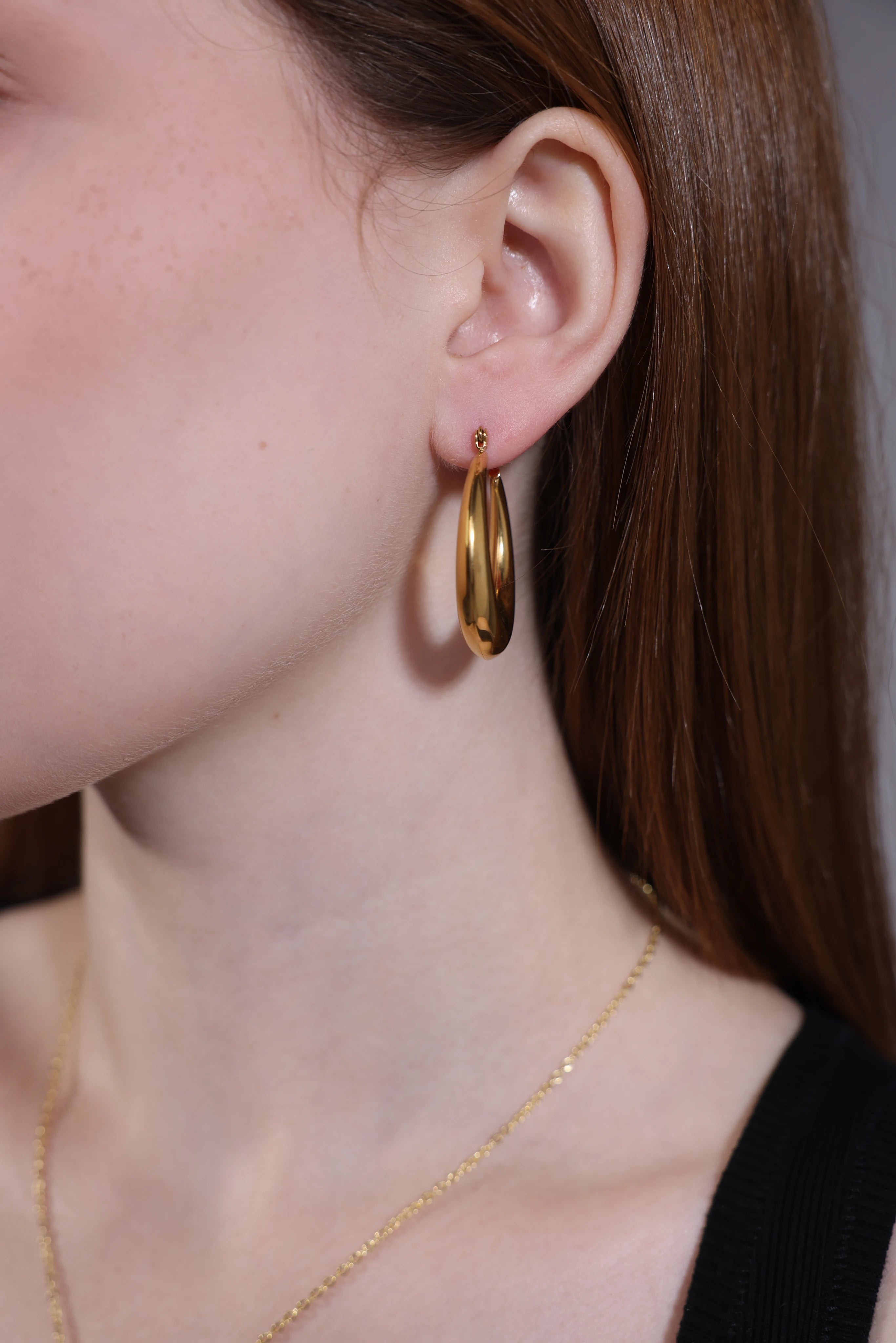 close-up side view of chunky oval gold hoop earrings