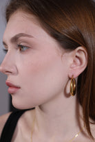 detailed close-up of chunky gold hoop earrings in polished 18K gold finish
