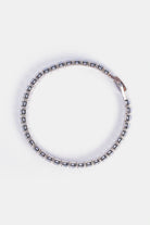 cubic zirconia tennis bracelet layered with minimalist jewelry