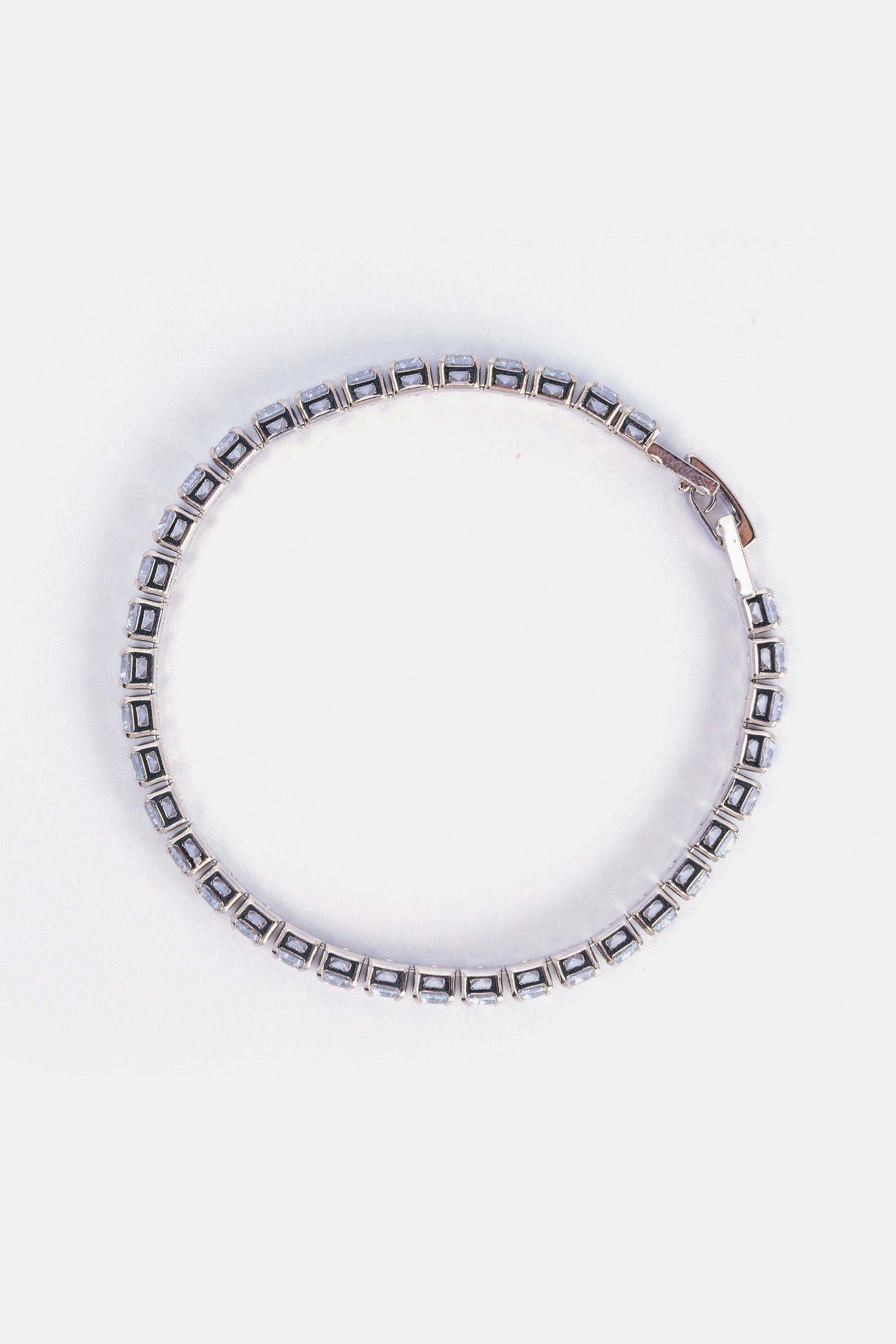 cubic zirconia tennis bracelet layered with minimalist jewelry