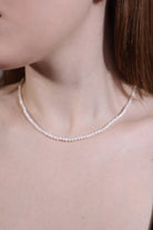 dainty white gemstone choker on neck – minimalist style
