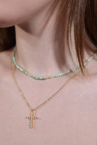 gold cross pendant necklace layered with beaded choker