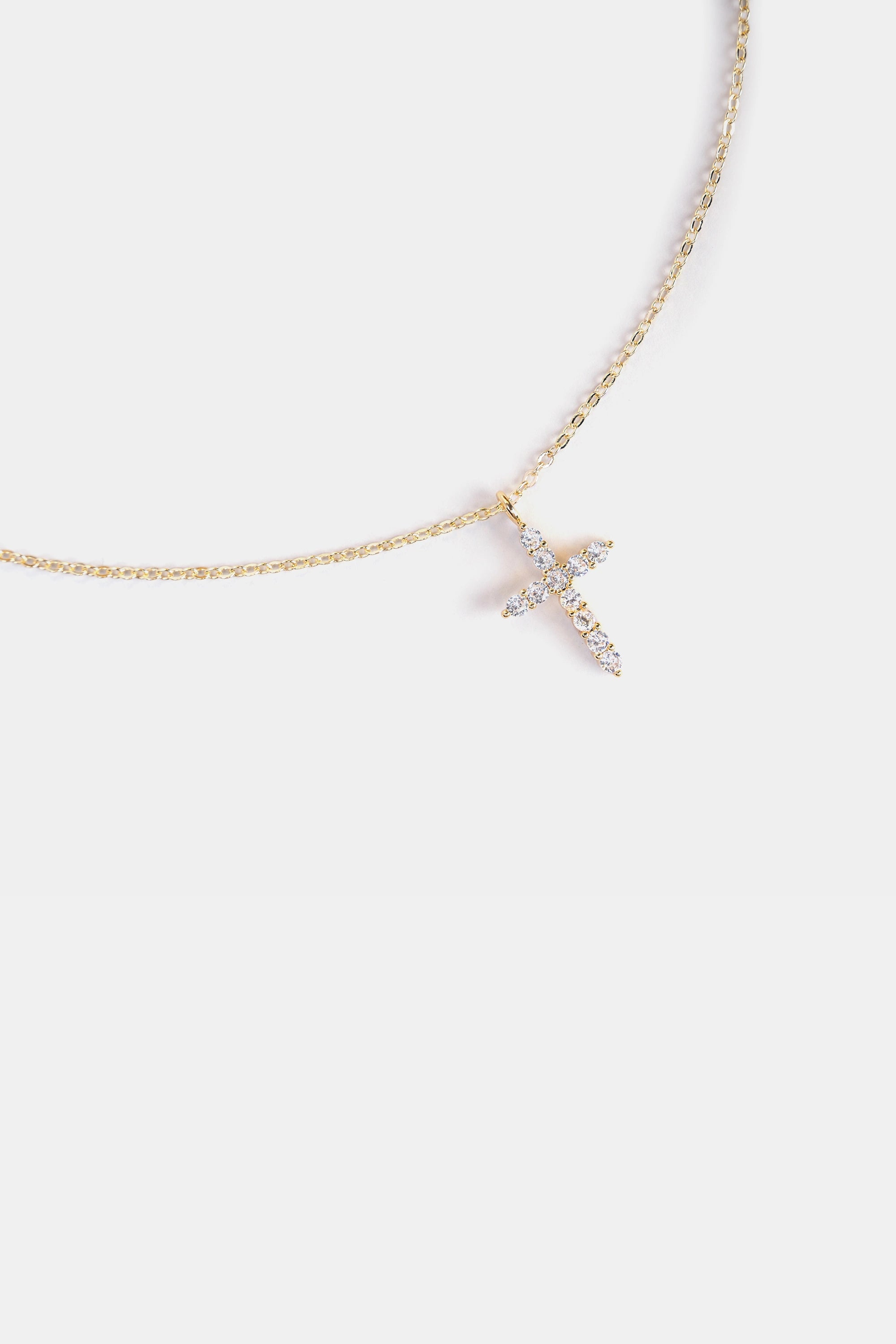 close-up of cubic zirconia cross pendant on gold chain