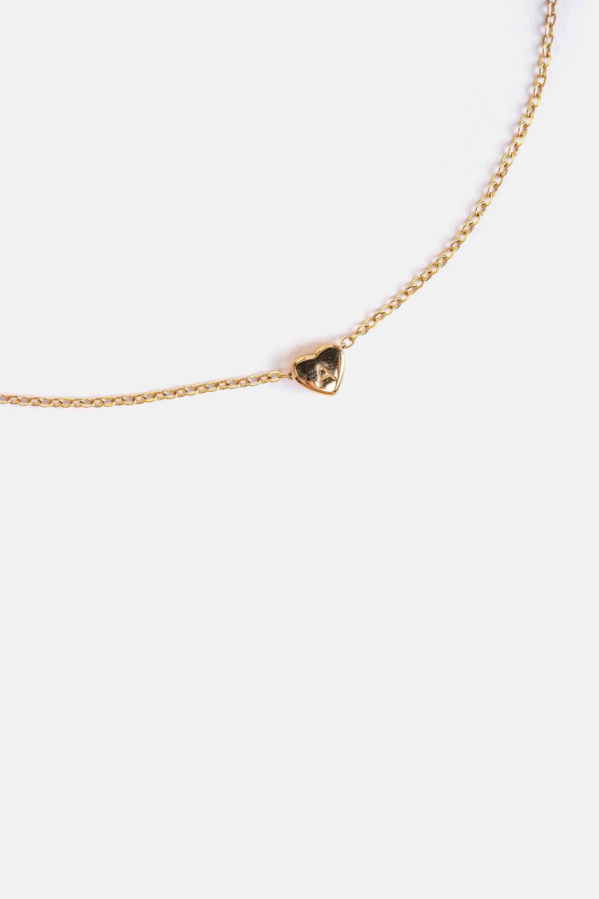 close-up of gold heart pendant with engraved A initial