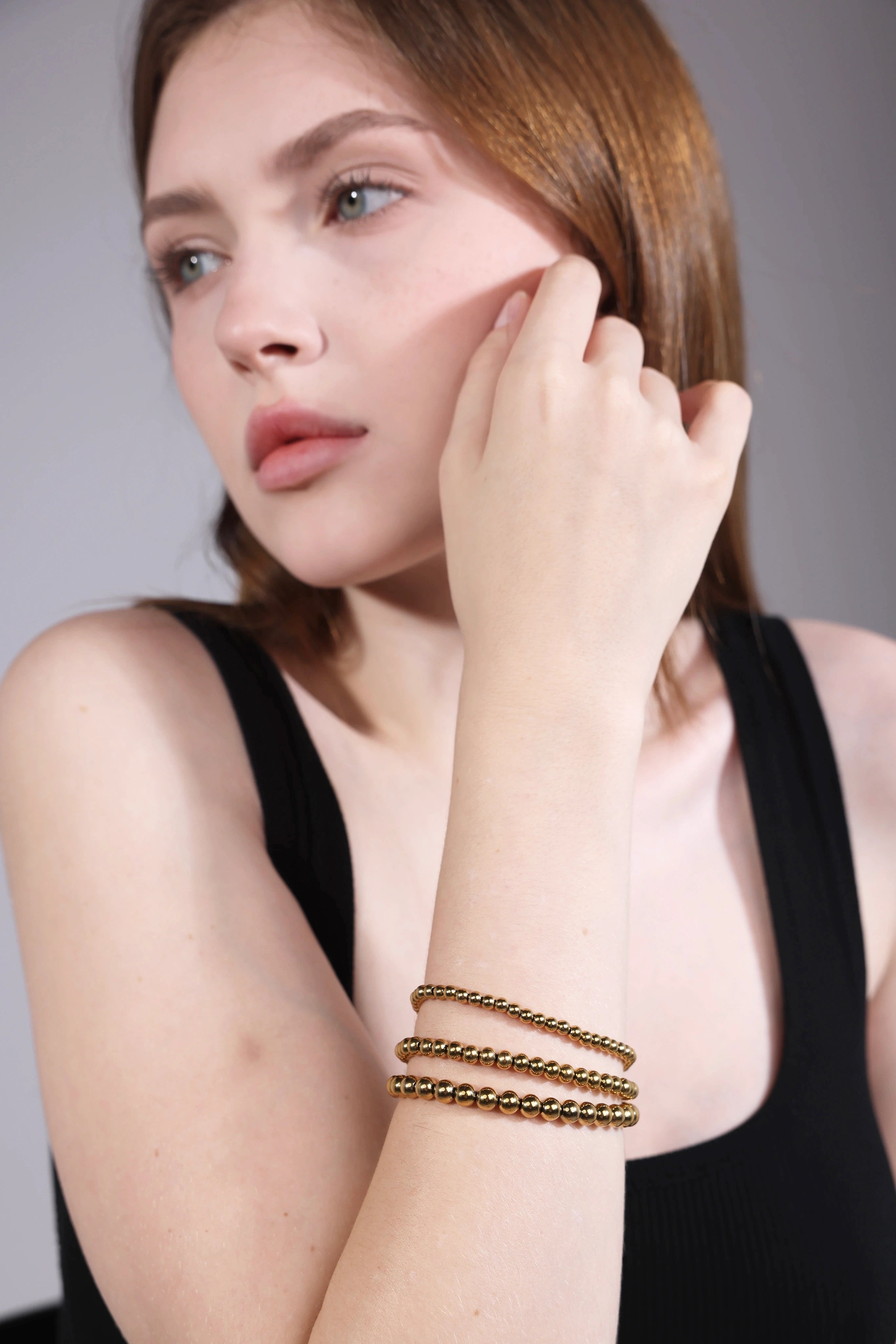 portrait of woman wearing gold minimalist beaded bracelet set