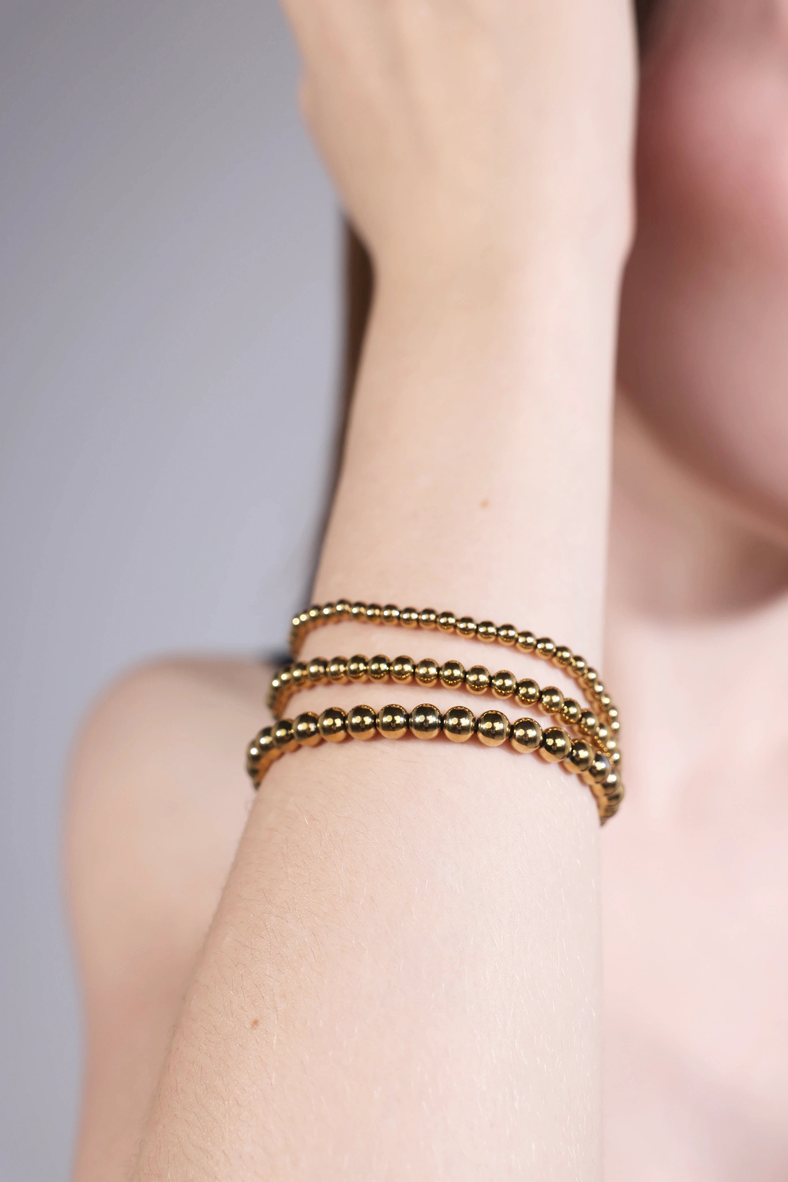 model wearing stackable gold beaded bracelets – minimalist layering style