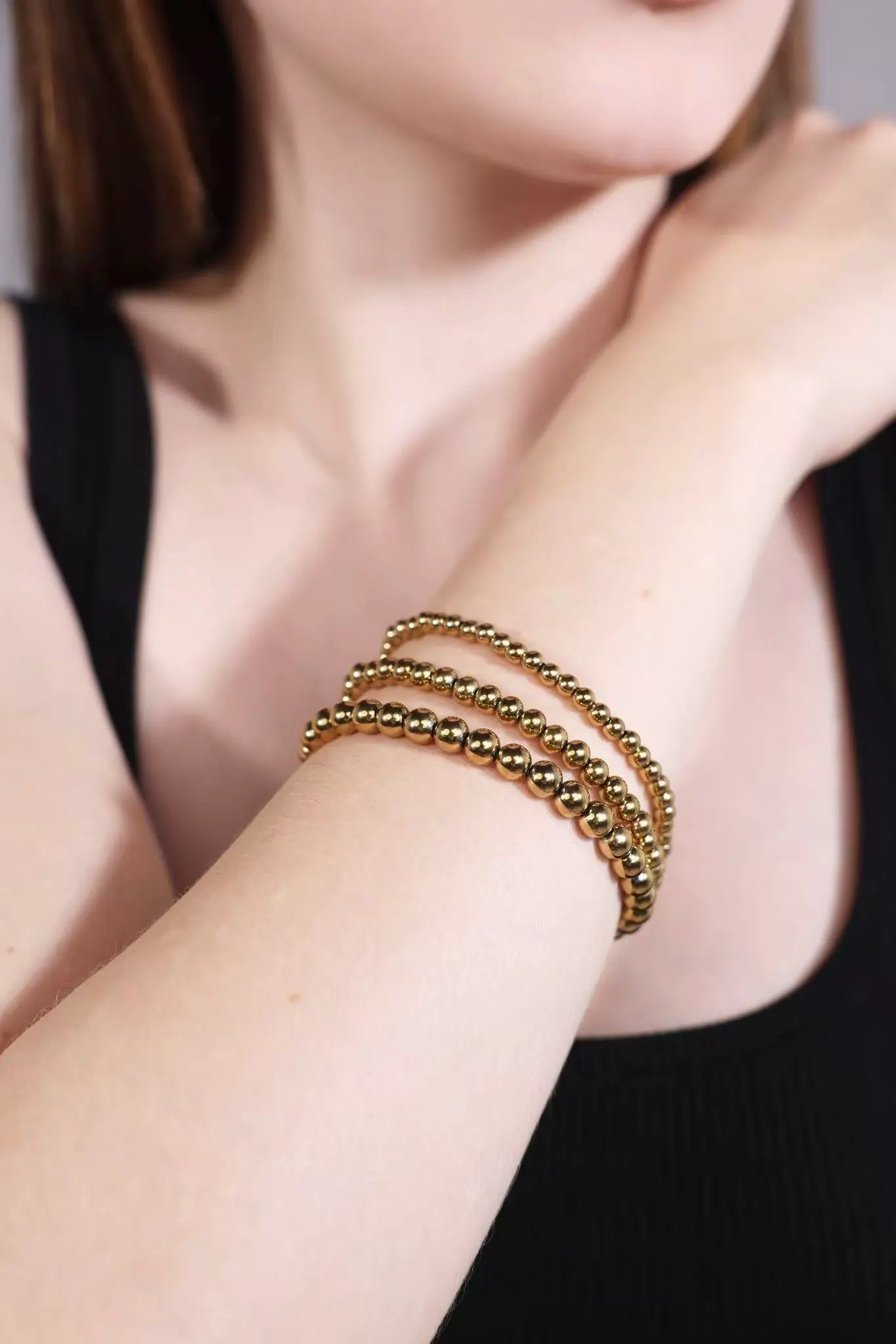 close-up of stacked gold beaded bracelets on wrist