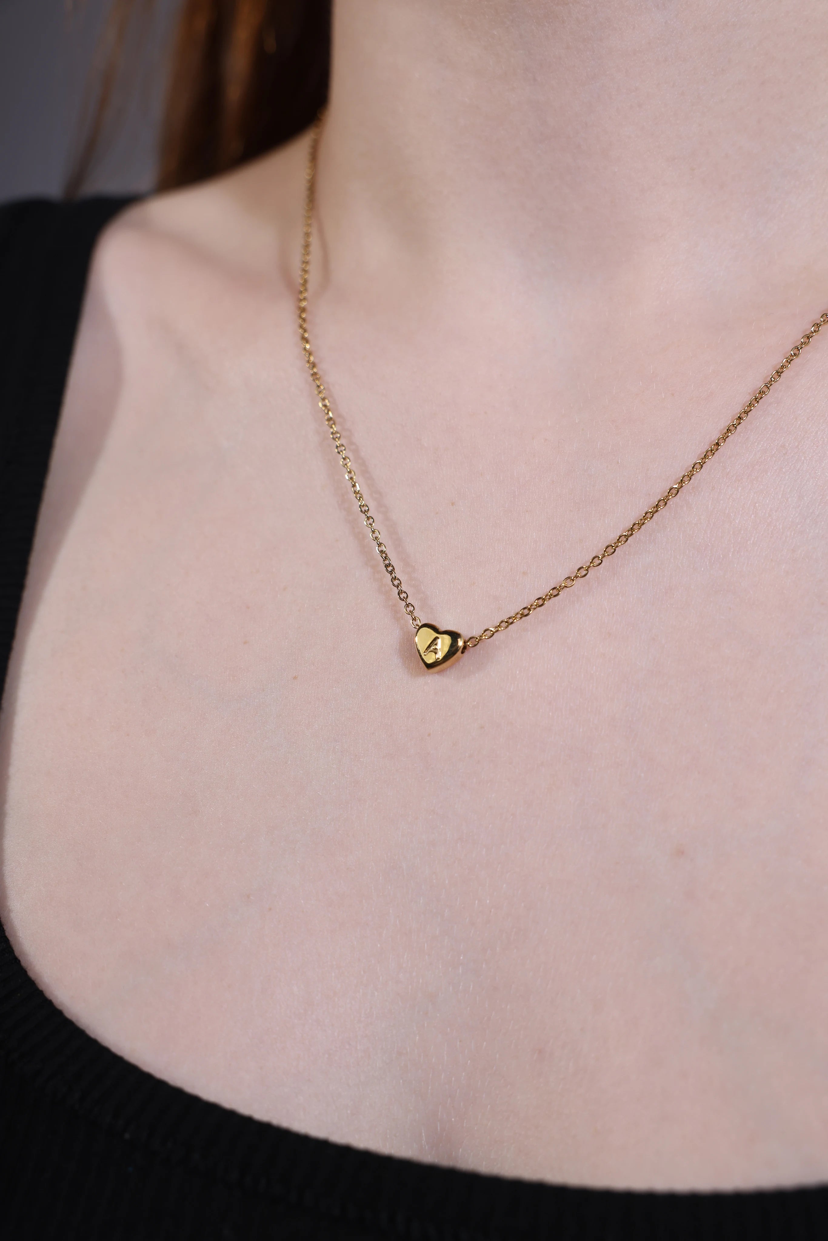 model wearing dainty gold heart initial necklace A