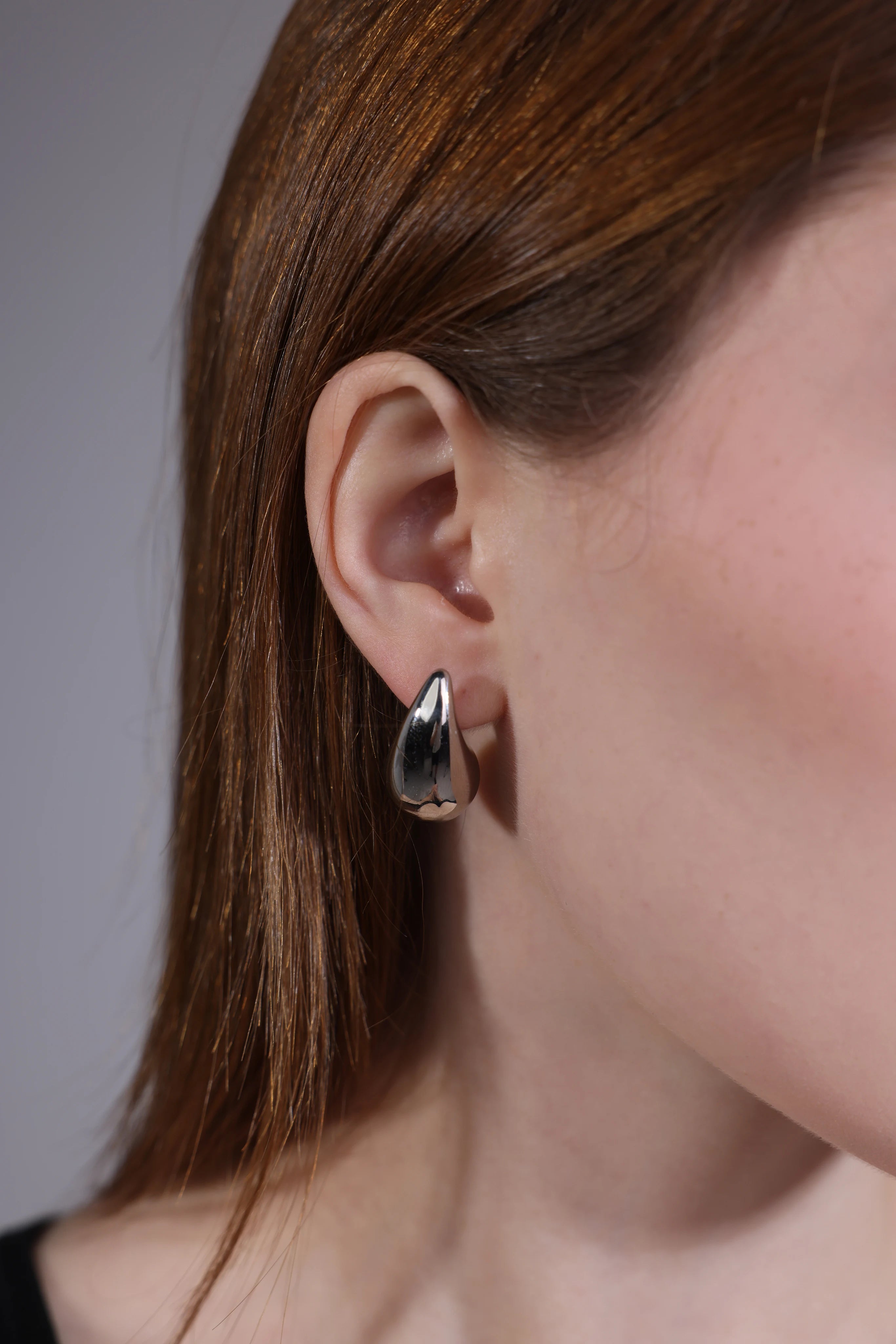 close-up of silver stainless steel teardrop hoop earrings – high polish finish