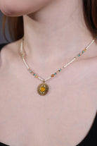 close-up of amber sun pendant choker with ivory and turquoise beads