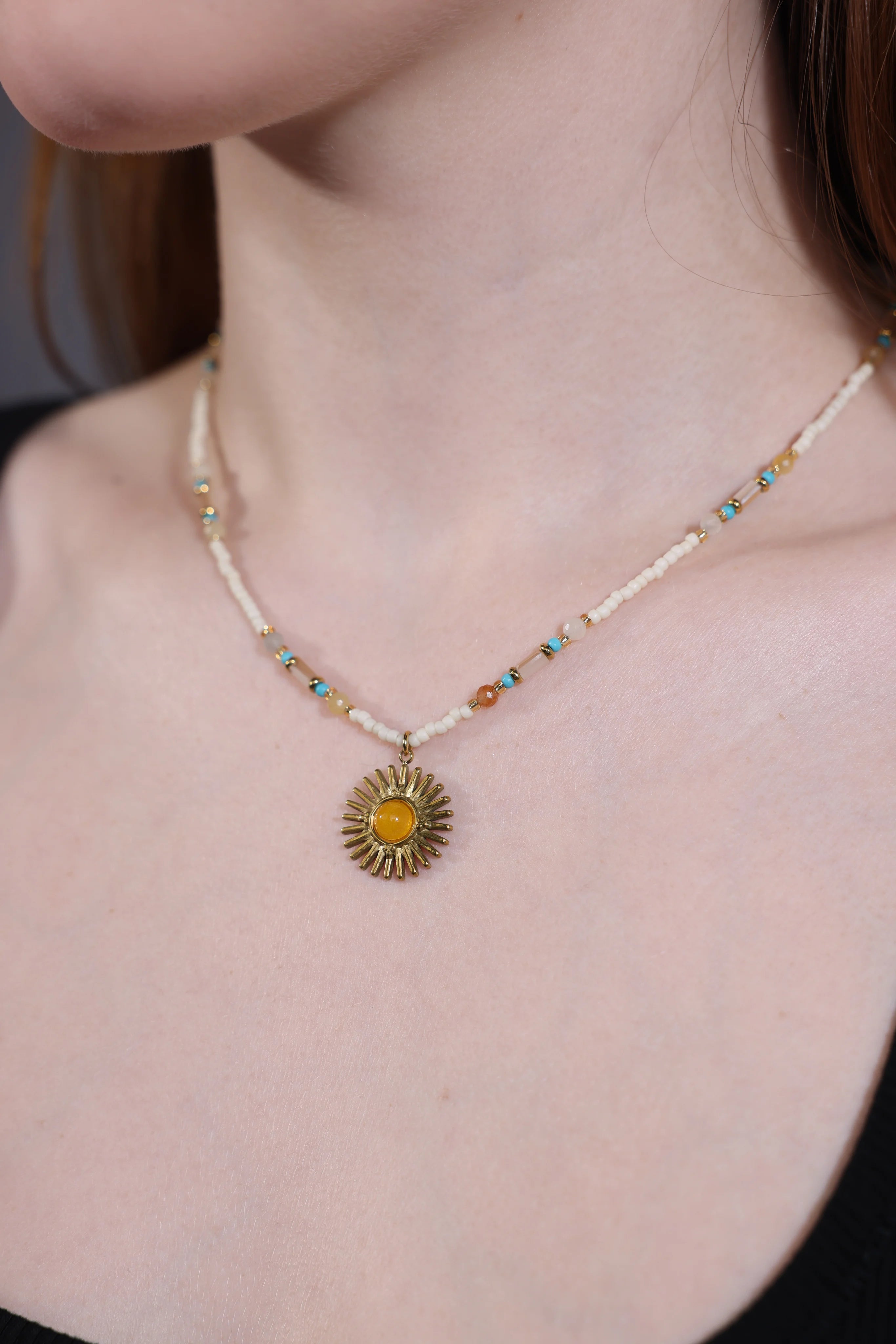 close-up of amber sun pendant choker with ivory and turquoise beads