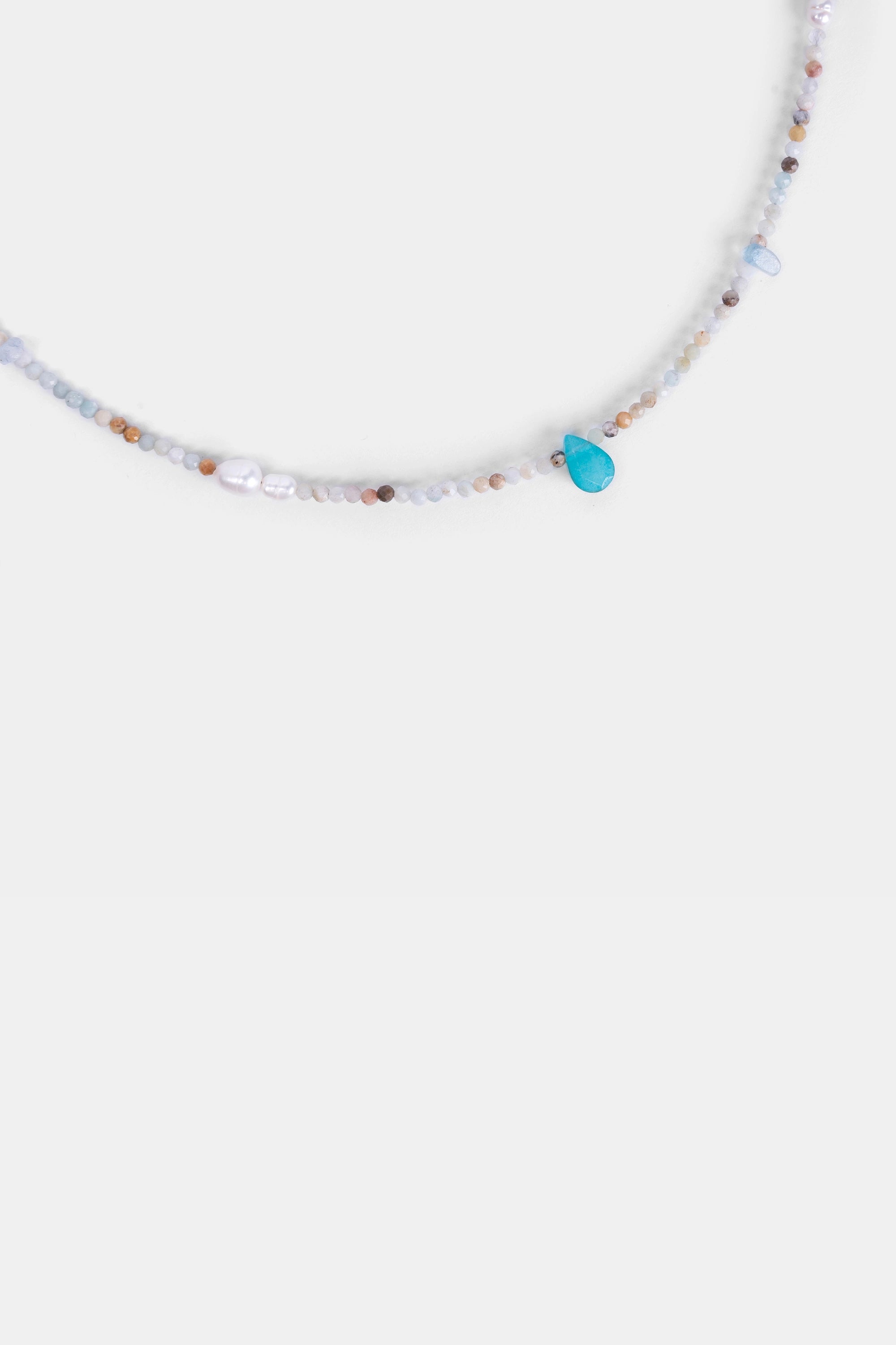 close-up of turquoise teardrop pendant with natural gemstone beads