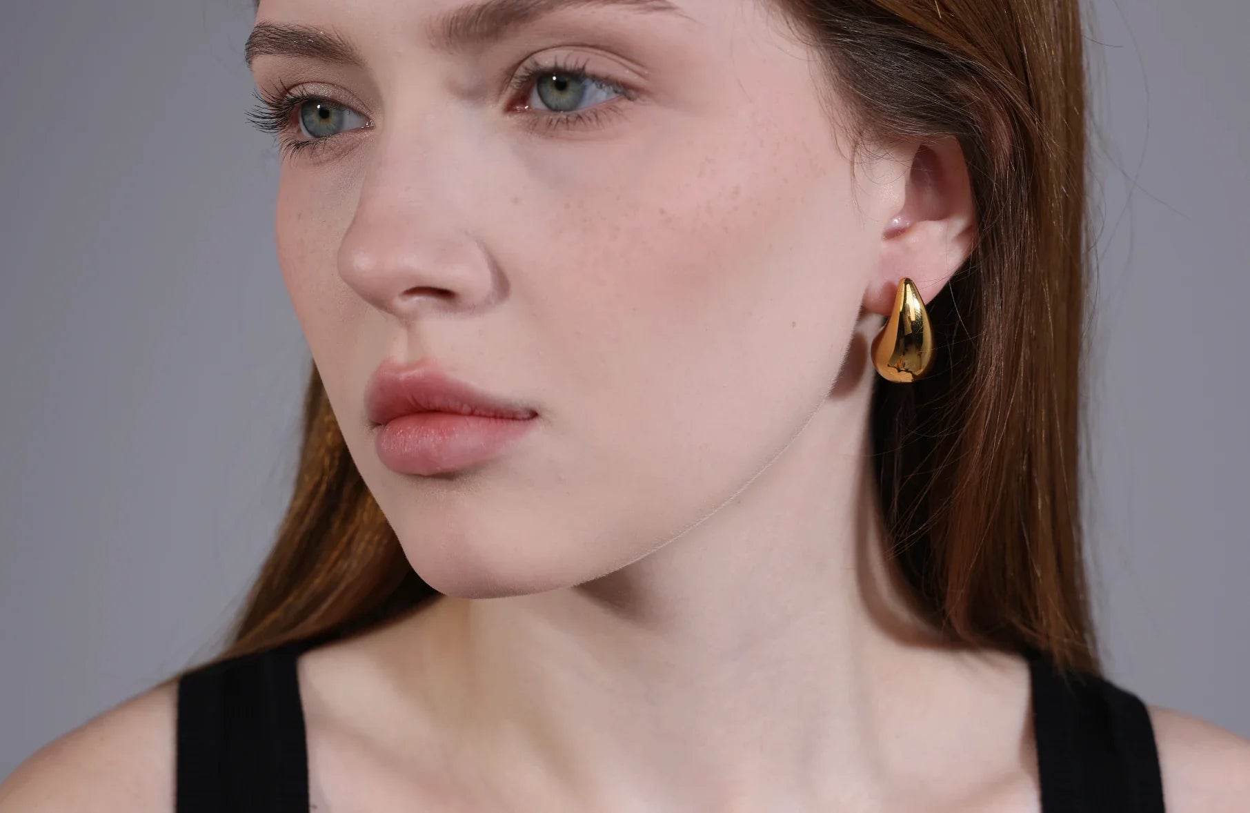 Model wearing chunky gold hoops – 18K gold plated jewelry by Velvet Luminance, hypoallergenic and tarnish resistant.