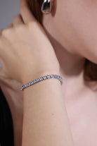 cubic zirconia tennis bracelet layered with minimalist jewelry